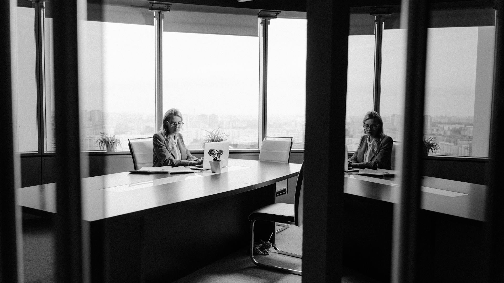 Caucasian woman in a modern office with a cityscape view, working with focus and poise.