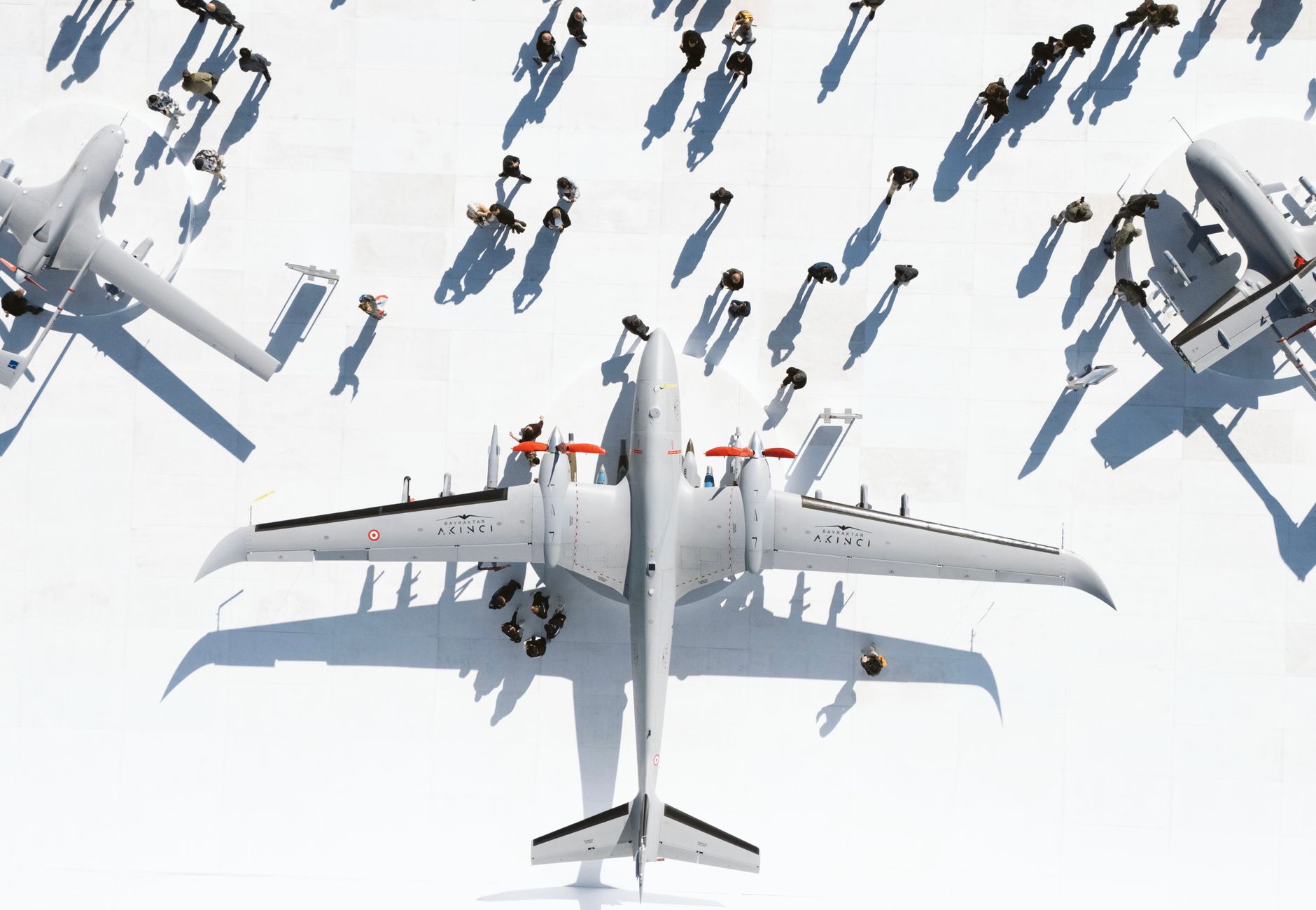 Aerial view of military jets with people and shadows on a sunny day.