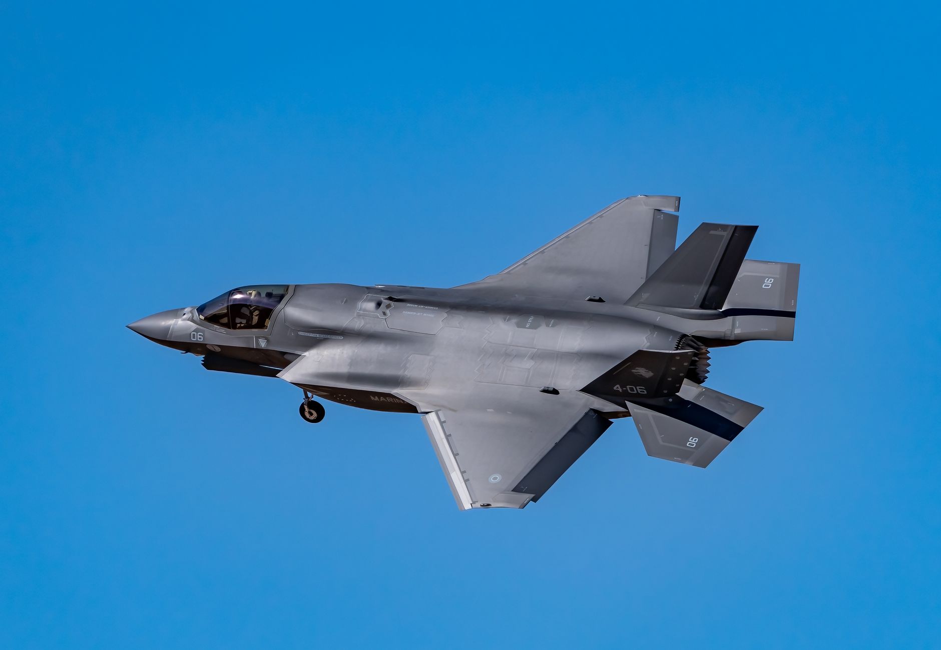 Dynamic shot of a F-35 fighter jet in flight against a clear blue sky.